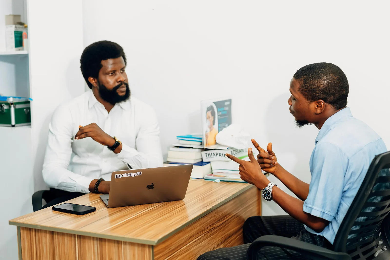 Two professionals in conversation across a desk in a bright office