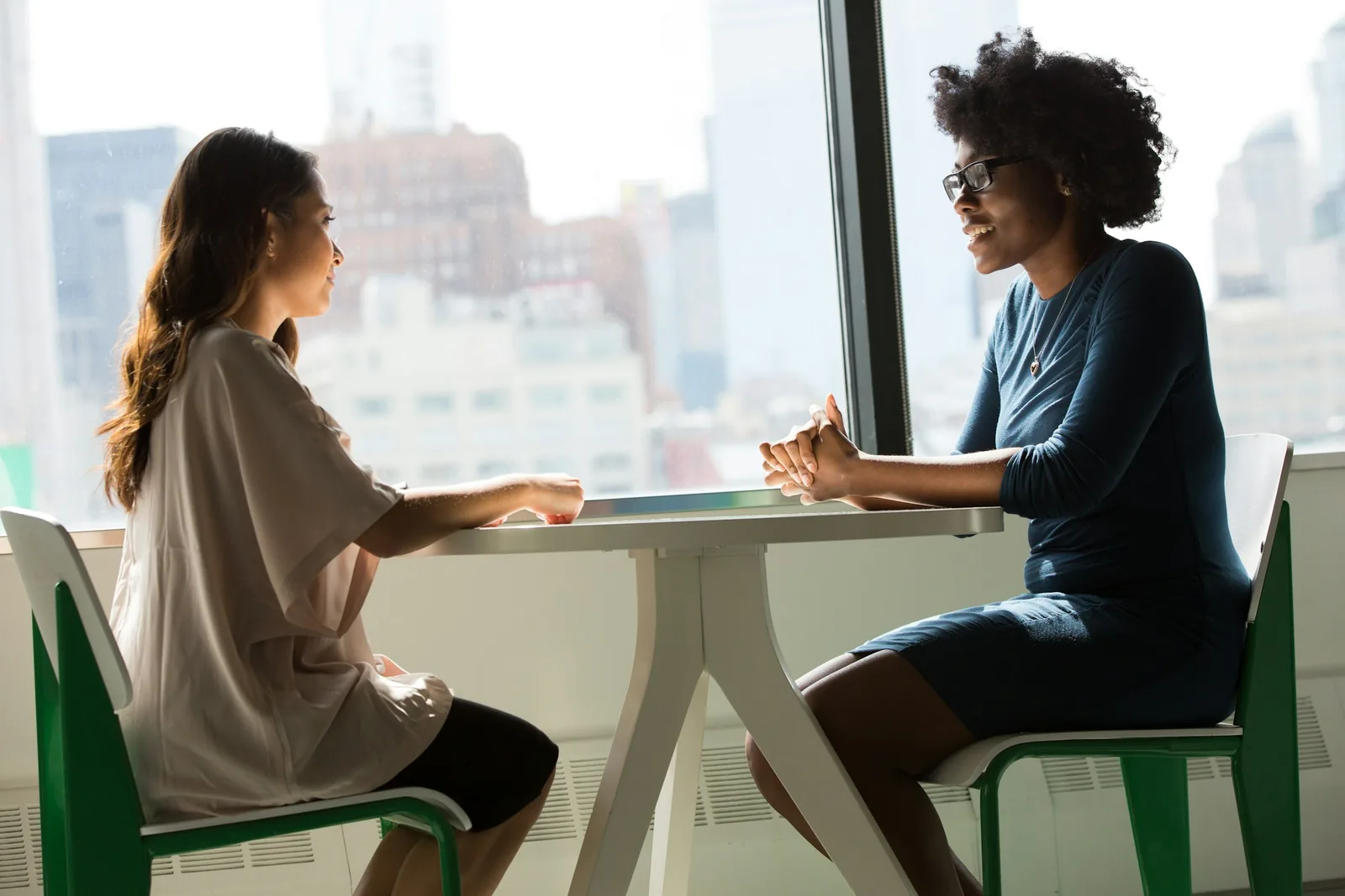 Two professionals in conversation at a table by a window